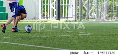 Soccer players in action on green grass field focusing on their legs and ball during game with bright outdoor background and sportswear 126214380