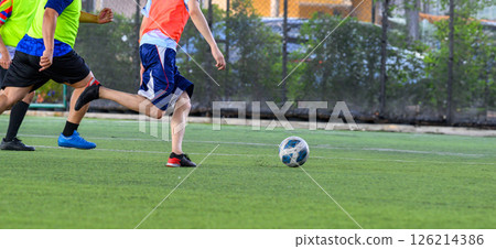 Soccer players in action on green grass field focusing on their legs and ball during game with vibrant sportswear and dynamic movement 126214386