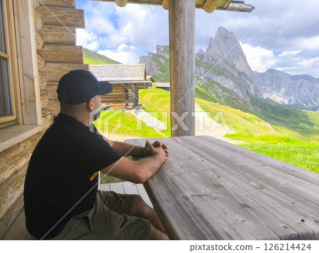 Relaxing at a mountain cabin while admiring breathtaking peaks under a partly cloudy sky in the Dolomites Relaxing at a mountain cabin while admiring breathtaking peaks under a partly cloudy sky in the Dolomites 126214424