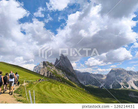 Hiking through scenic mountain trails in the Dolomites under a stunning blue sky 126214431