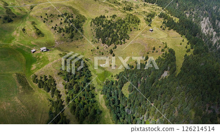 Expansive green hills and rustic cabins nestled in a serene landscape at golden hour Expansive green hills and rustic cabins nestled in a serene landscape at golden hour 126214514