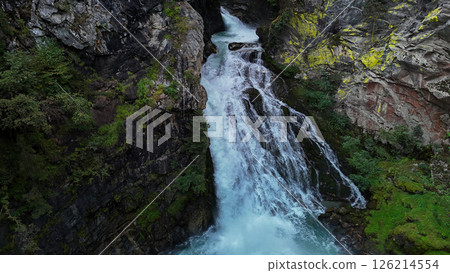 Majestic waterfall cascades down rocky cliffs in a serene forest setting at the heart of nature's untouched beauty Majestic waterfall cascades down rocky cliffs in a serene forest setting at the heart of nature's untouched beauty 126214554