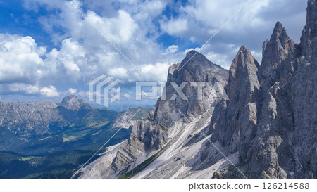 Serene mountain landscape under a vibrant blue sky adorned with fluffy clouds during a sunny day in the Dolomites 126214588