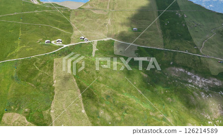 Expansive green valleys dotted with quaint cottages under a clear blue sky in the alpine region Expansive green valleys dotted with quaint cottages under a clear blue sky in the alpine region 126214589