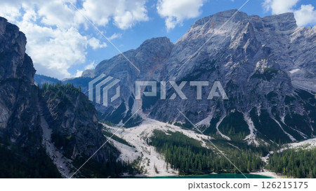 Majestic mountains tower over serene lake with lush pine forests at dawn near Lago di Braies Majestic mountains tower over serene lake with lush pine forests at dawn near Lago di Braies 126215175