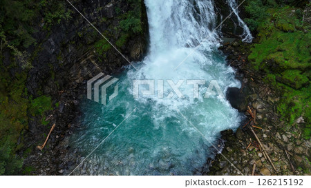 Majestic waterfall cascades into a tranquil turquoise pool amidst lush green forest in the heart of nature's beauty Majestic waterfall cascades into a tranquil turquoise pool amidst lush green forest in the heart of nature's beauty 126215192