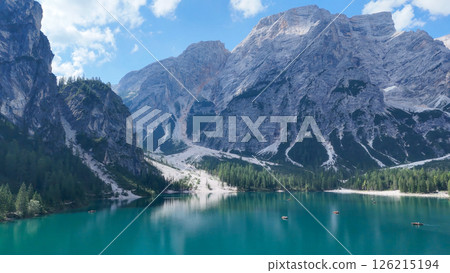 Majestic mountains rise over tranquil turquoise waters in a serene alpine landscape during sunny midday 126215194