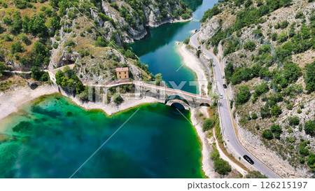 Serene waters and winding roads showcase the beauty of nature around a historic bridge in a remote landscape Generative AI 126215197