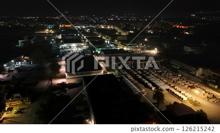 Urban nightscape showcasing vibrant industrial activity illuminated by glowing lights and a serene backdrop of distant hills Generative AI 126215242