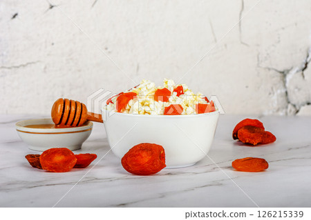 Dried apricots in fresh cottage cheese with honey. 126215339