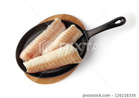 three pieces of fish fillet on black cast iron frying pan isolated on white background. cod steaks prepared for frying top view with copy space 126216330