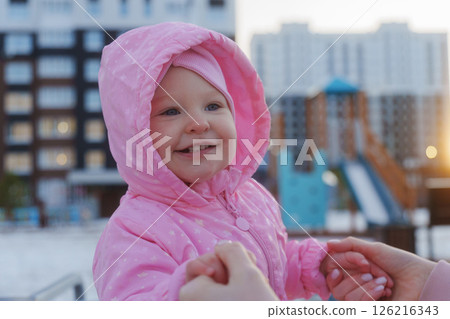 Happy child in pink jacket enjoys playtime at playground during sunset in a modern urban setting Happy child in pink jacket enjoys playtime at playground during sunset in a modern urban setting 126216343