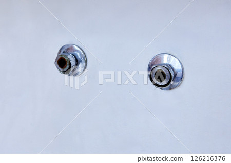 Two exposed metal pipe outlets with chrome escutcheons protrude from smooth white wall after removal of old wall mounted faucet, showing slight corrosion. 126216376