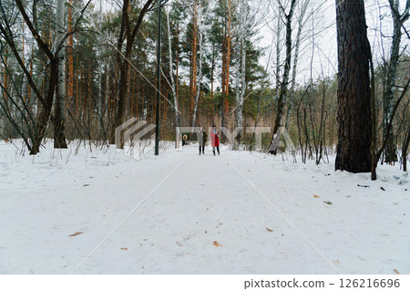 Two people walking in a snowy forest landscape during winter months in a remote area 126216696