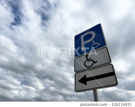 Handicap parking sign with directional arrow on cloudy day, indicating accessible parking for people with disabilities, promoting inclusion and barrier free infrastructure Handicap parking sign with directional arrow on cloudy day, indicating accessible parking for people with disabilities, promoting inclusion and barrier free infrastructure 126216931