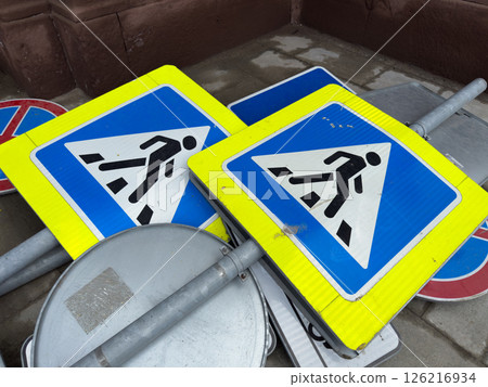 Decommissioned pedestrian crossing signs stacked on the ground as part of an urban infrastructure update. Symbolic representation of modernization and street renovation in the city Decommissioned pedestrian crossing signs stacked on the ground as part of an urban infrastructure update. Symbolic representation of modernization and street renovation in the city 126216934