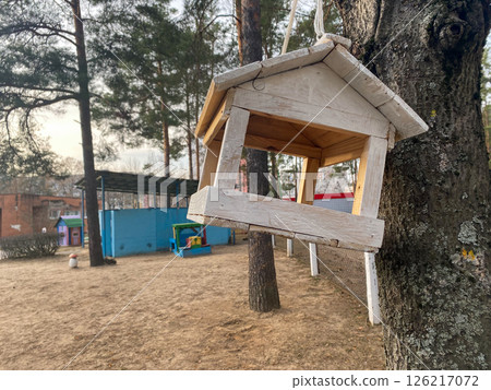 A wooden birdhouse for birds hangs from a tree on a children's playground 126217072