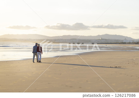 Senior couple walking on the beach at sunset, enjoying retirement 126217086