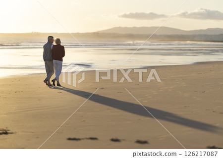 Senior couple walking on the beach at sunset 126217087