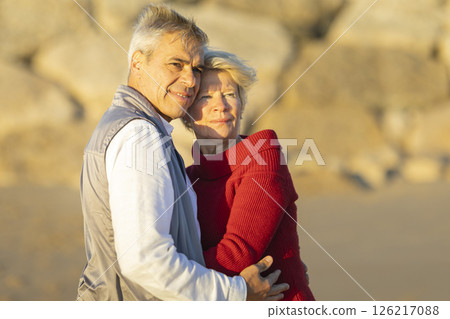 Senior couple embracing on beach at sunset, enjoying retirement together 126217088