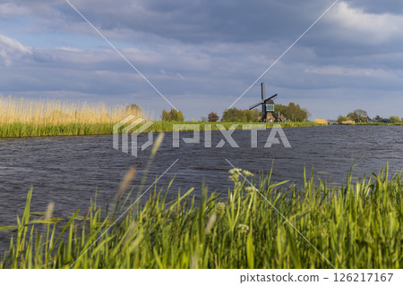 Traditional Dutch windmill standing on the bank of a canal in Brandwijk, Netherlands Traditional Dutch windmill standing on the bank of a canal in Brandwijk, Netherlands 126217167