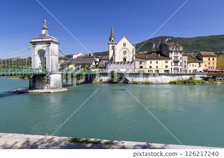 Seyssel suspension bridge over turquoise Rhone River in Ain, France, with church and colorful houses 126217240