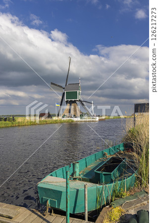 Traditional Dutch windmill standing tall along canal with moored boat in Groot Ammers, Netherlands 126217273