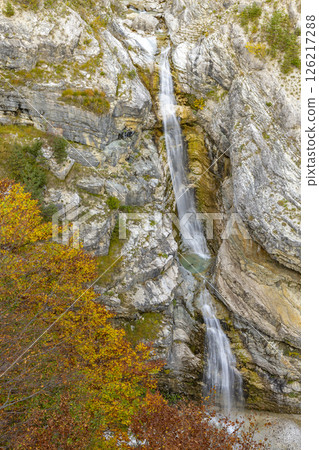 Virje waterfall cascading down rocky cliff in Bovec, Slovenia during autumn foliage 126217288