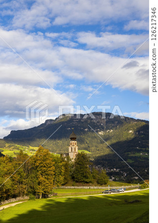 St. Valentin church rising above autumn trees in dolomites, italy 126217346