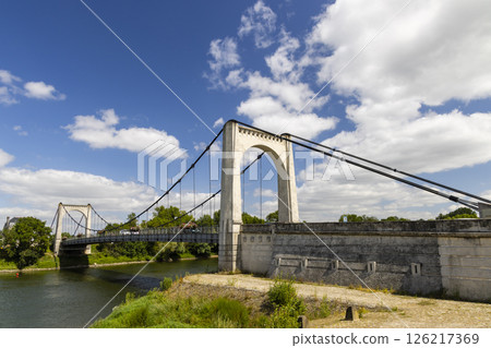 Suspension bridge crossing the Loire River in Chalonnes sur Loire, France, under a cloudy sky 126217369