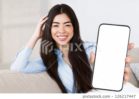 Cozy Lifestyle. Portrait of smiling asian girl sitting on couch cuddling pillow, relaxing at home and posing at camera, free space Cozy Lifestyle. Portrait of smiling asian girl sitting on couch cuddling pillow, relaxing at home and posing at camera, free space 126217447