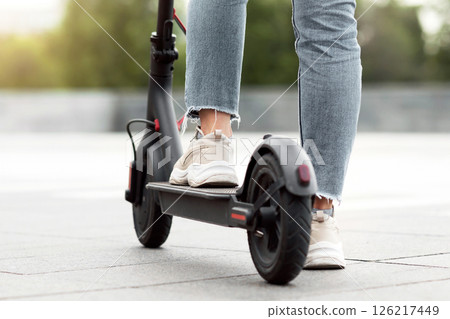 Electric Vehicles. Closeup back view of unrecognizable person standing on black e-scooter, selective focus, copy space 126217449