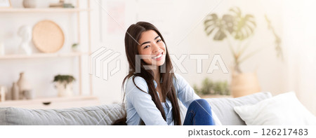 Home Comfort. Portrait Of Beautiful Asian Girl Posing On Sofa In Living Room, Smiling At Camera 126217483