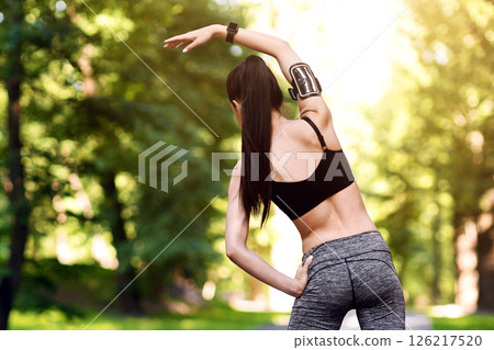 Fitness Training Outdoors. Full-length shot of sporty female warming up before running in park, rear view with free space Fitness Training Outdoors. Full-length shot of sporty female warming up before running in park, rear view with free space 126217520