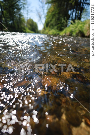 The water is clear and calm, with a few rocks scattered throughout 126217728