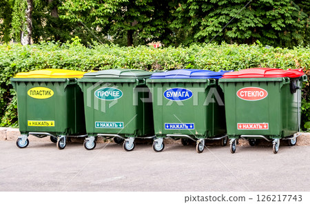 Green plastic dumpsters on a city street with inscription on russian: " Plastic", "Other", "Paper", "Glass", "Press on" Green plastic dumpsters on a city street with inscription on russian: " Plastic", "Other", "Paper", "Glass", "Press on" 126217743