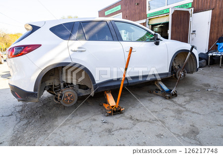 Car without wheels and lift up by jack stand .Waiting for tire replacement. 126217748