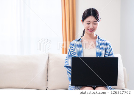 Young woman relaxing at home and using a laptop Young woman relaxing at home and using a laptop 126217762