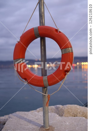 Red life preserver is hanging from a metal pole 126218610