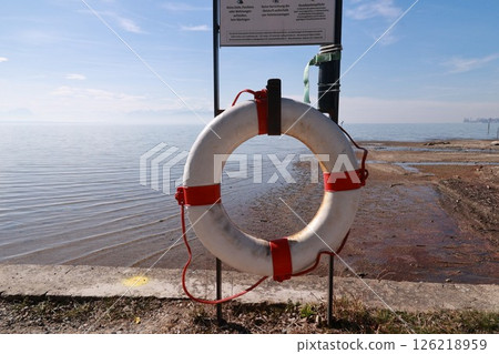 A white life preserver is on a post by the water 126218959
