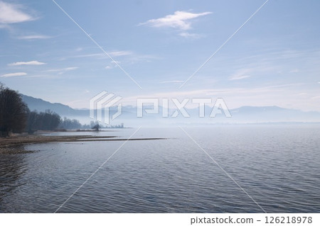 A calm lake with a cloudy sky in the background A calm lake with a cloudy sky in the background 126218978