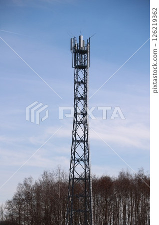Tall tower with a lot of antennas on top 126219362