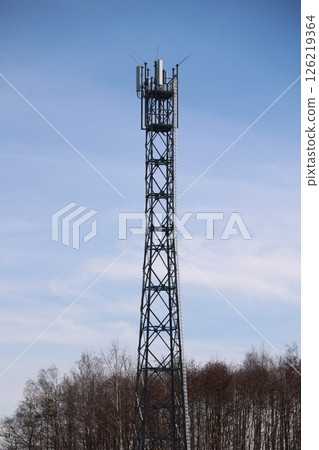 Tall tower with a lot of antennas on top 126219364