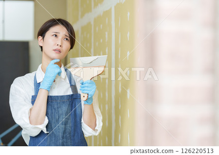 A woman doing DIY applying putty to plasterboard A woman doing DIY applying putty to plasterboard 126220513