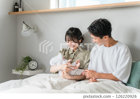 Mom and dad holding a baby in the bedroom/bedroom (childcare) Mom and dad holding a baby in the bedroom/bedroom (childcare) 126220926