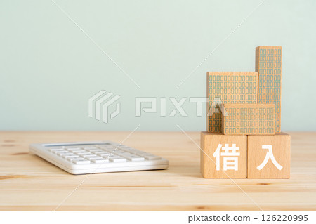 A block with the word "loan" written on it, a calculator, and a model of a real estate property A block with the word "loan" written on it, a calculator, and a model of a real estate property 126220995
