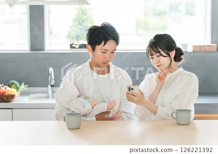 A young Asian couple who is having trouble raising children and looks it up on their smartphone 126221392