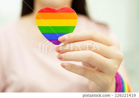Asian woman holding LGBT heart with rainbow flag. Asian woman holding LGBT heart with rainbow flag. 126221419