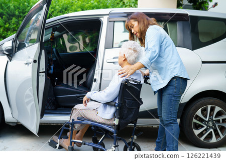 Caregiver help Asian elderly woman disability patient use wheelchair to get in car. 126221439