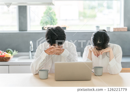 A young couple looking down while looking at a computer (losing election, being shocked, being scammed, being deceived) 126221779